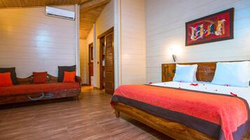 Quarto de hotel com cama de madeira, um sofá e um quadro na parede.