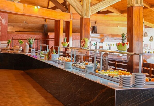 Zona de bufé con diversas opciones de comida y frutas decorativas.