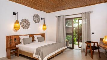A bedroom with a wooden bed, two wall-mounted lamps, a wooden nightstand, a small table with a lamp, and a sliding glass door leading to a balcony.