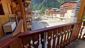 A wooden balcony with a view of a mountain resort area, including buildings and a parking lot. - Cozy Studio with Cabin for 4/5 People, Near Ski Lifts - Modane, France (Valfréjus)