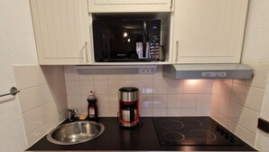 A compact kitchen with a built-in microwave, a coffee maker, a sink, and a dishwasher. - Cozy Studio with Cabin for 4/5 People, Near Ski Lifts - Modane, France (Valfréjus)