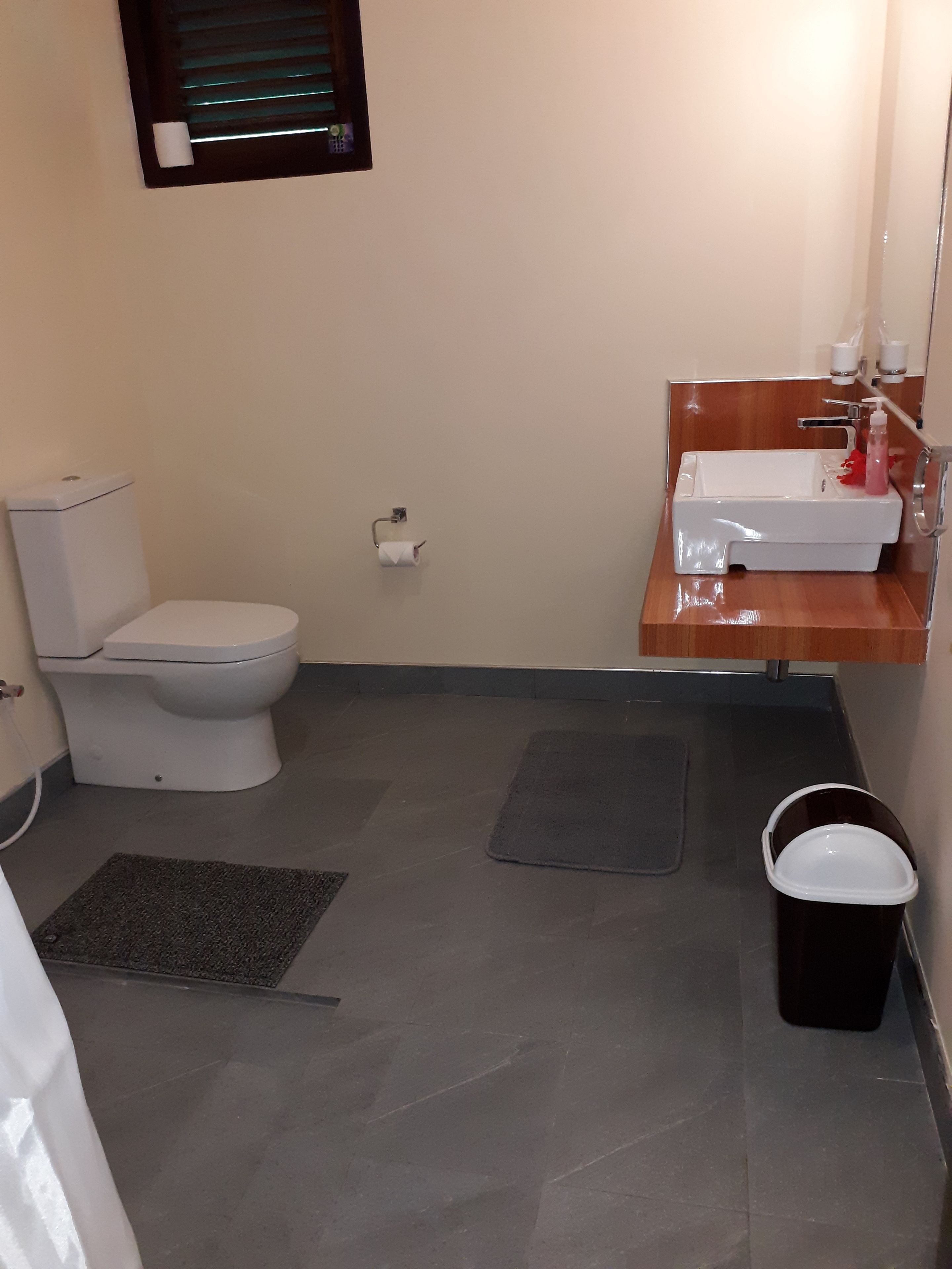 A small bathroom with a toilet, sink, and a mirror.