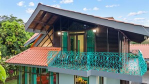 Une maison moderne avec un toit en pente, de grandes fenêtres et un balcon agrémenté d’une balustrade décorative.
