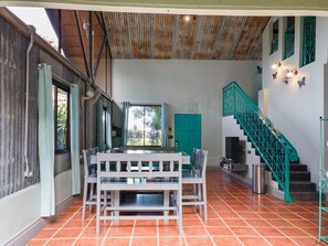 A spacious room with a dining table and chairs, a staircase with decorative railings, and a view through a window. - CASA TURQUESA Tropical Retreat in La Fortuna (LA FORTUNA DE SAN CARLOS)