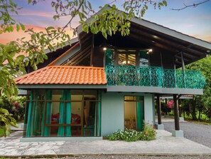 A modern house with a tiled roof, large windows, and a balcony with decorative railing. - CASA TURQUESA Tropical Retreat in La Fortuna (LA FORTUNA DE SAN CARLOS)