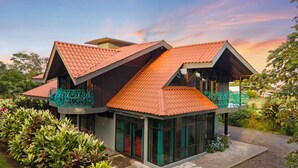 Une maison moderne dotée d’un toit au design original, de grandes fenêtres et d’un jardin bien entretenu.