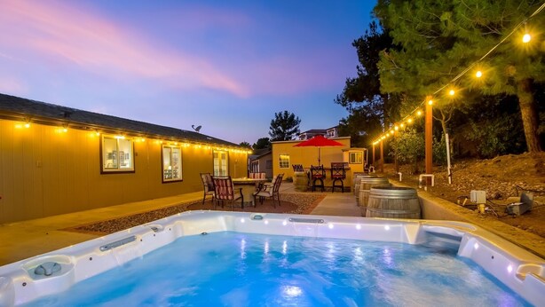 Ein Garten mit Whirlpool, Sitzgelegenheiten im Freien und Lichterketten.