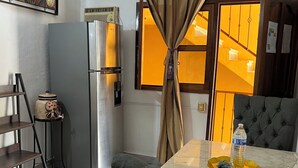 A modern kitchen with a stainless steel refrigerator, a dining table with a water bottle, and a grey sofa. - A peaceful apartment in sun house Puerto Vallarta (Lomas del Calvario)