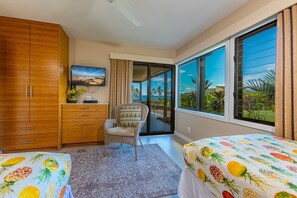 A bedroom with two beds, a wooden wardrobe, a chair, a TV, and a large window with a view of palm trees and a beach. - Stunningly Renovated! Ocean View! Elua 2305 (Wailea)