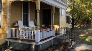 A two-story house with a covered porch, white chairs, and a small garden area. - Historic Home With Modern Amenities - Great for Families with room for up to 18! (Clear Lake)