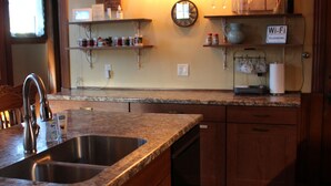 A kitchen with wooden cabinets, a granite countertop, a sink, a clock, and a Wi-Fi sign. - Historic Home With Modern Amenities - Great for Families with room for up to 18! (Clear Lake)
