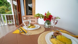 A dining table with plates of food, cutlery, and a vase of flowers. - La Maison Hibiscus (Mahé Island)