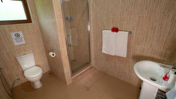 A bathroom with a toilet, shower, and sink.