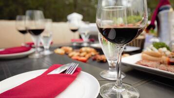 Una mesa de comedor con un mantelino rojo, una copa de vino y platos de comida.