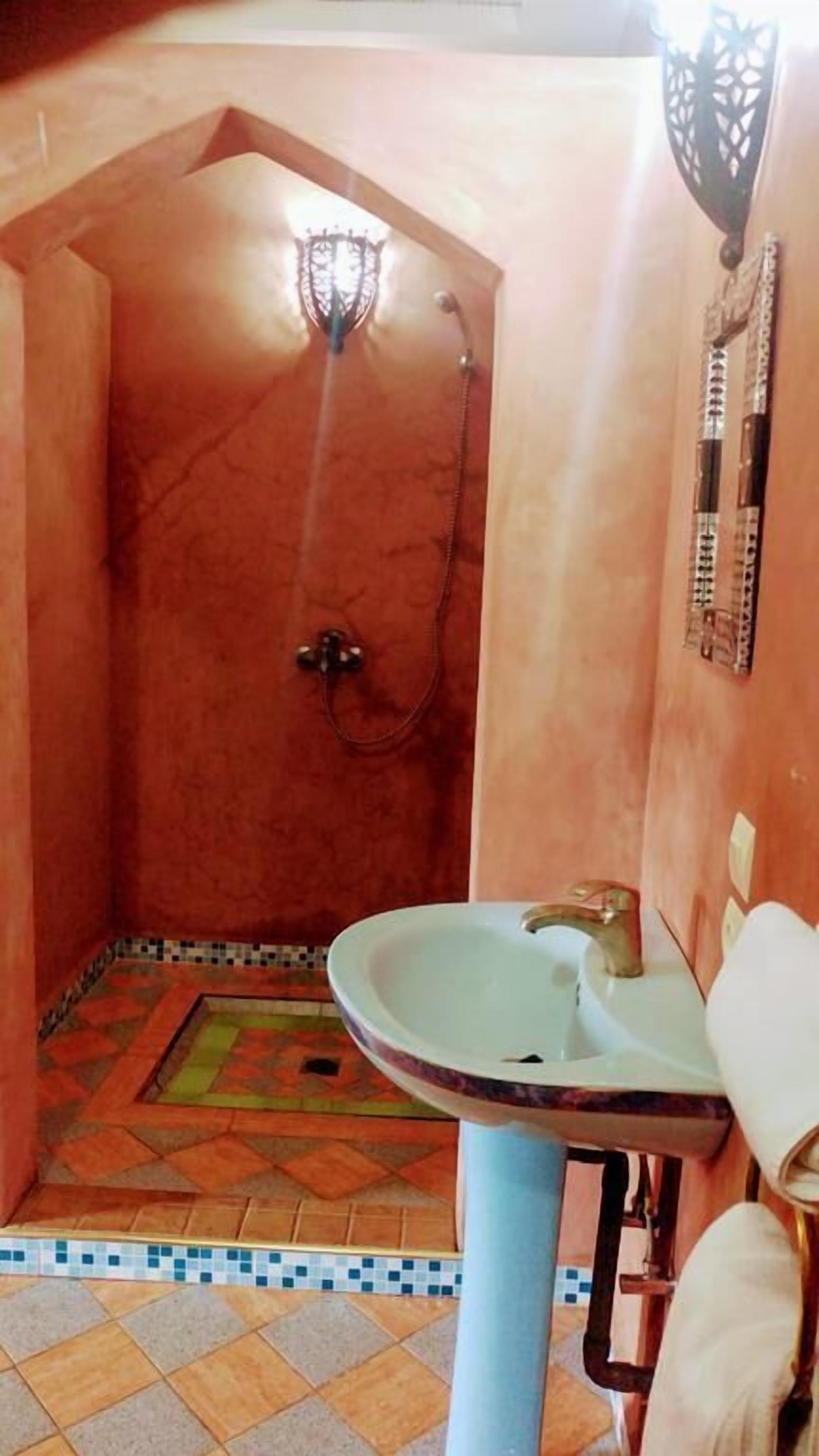 A bathroom with a shower, a sink, and a tiled floor.