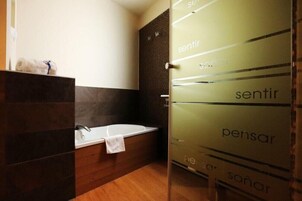 Un baño moderno con bañera, cabina de ducha de vidrio y una toalla en el lavabo.