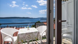 A balcony with a table and chairs, overlooking a body of water and distant land.