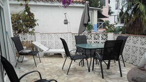 An outdoor patio with stone flooring, a glass table, and black chairs. - Villa in a very quiet and nice neighborhood. Dogs allowed. Jacuzzi possible. (Fuengirola)