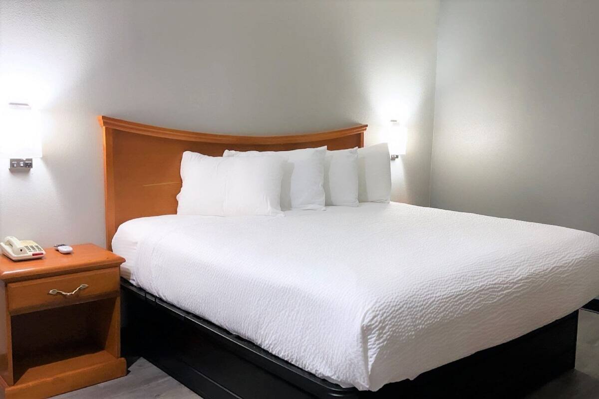 A hotel room with a single bed, a nightstand with a phone, and a door.