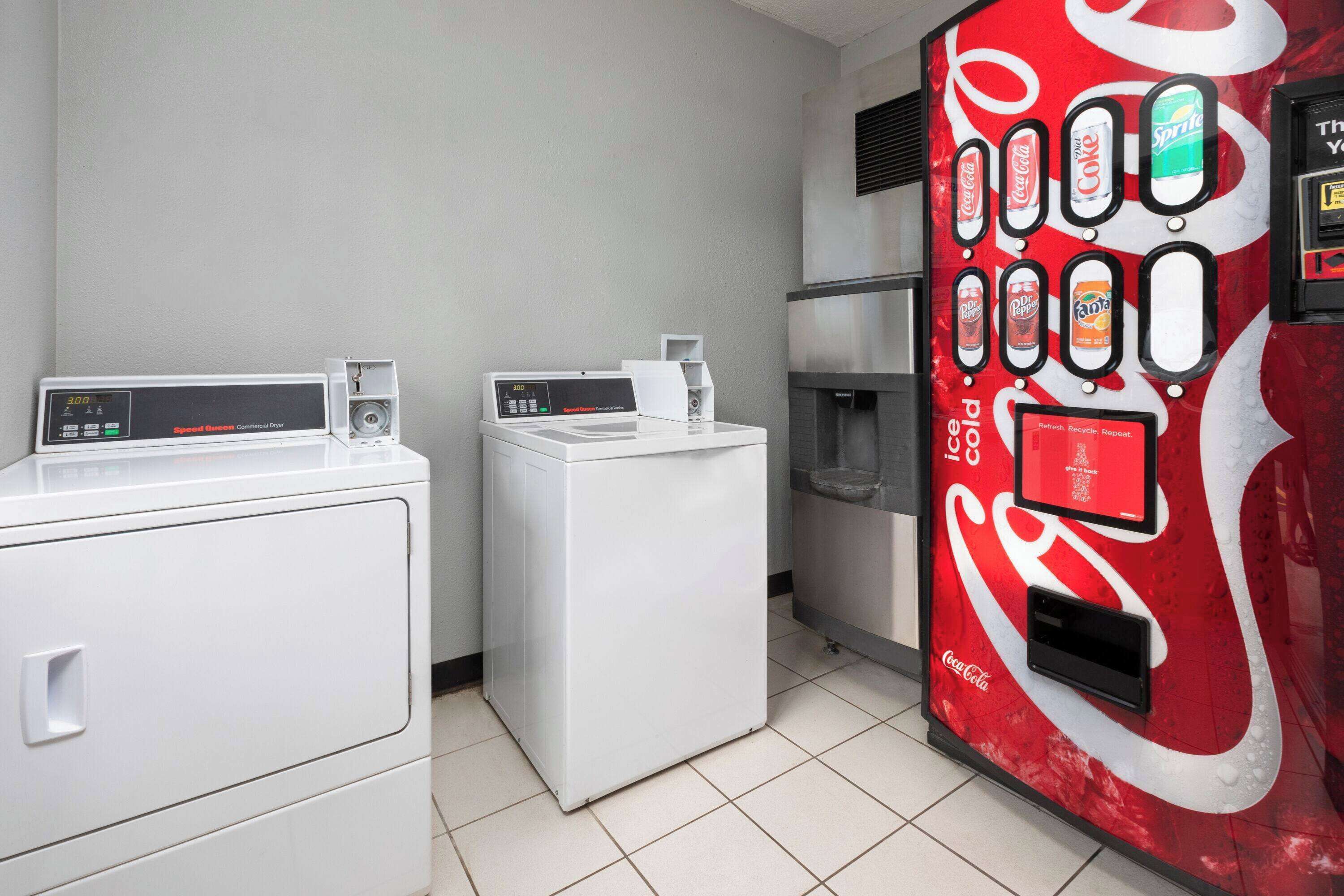 Ein Waschbereich mit zwei Waschmaschinen und einer Coca-Cola-Getränkeautomaten.