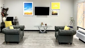 A modern living room with two grey sofas, a flat-screen TV, and framed pictures on the wall. - Days Inn by Wyndham North Little Rock/ Maumelle (North Little Rock)