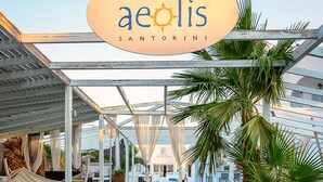 A resort with a white picket fence, outdoor seating, and palm trees. - Aeolis Santorini (Santorini)