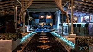 A covered outdoor area with a pool, a bar, and a restaurant. - Aeolis Santorini (Santorini)
