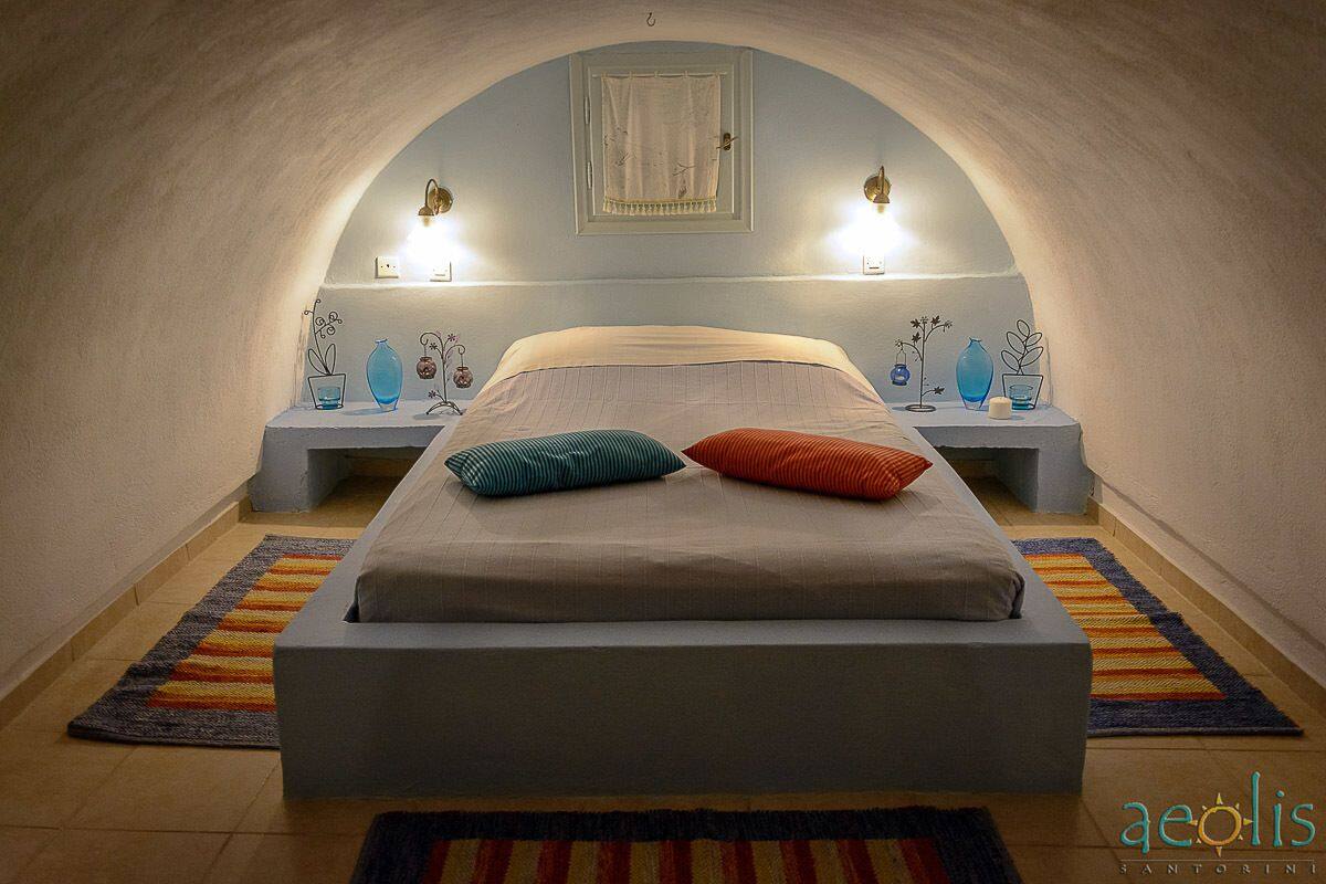 A bedroom with a bed, two bedside tables, and a window.
