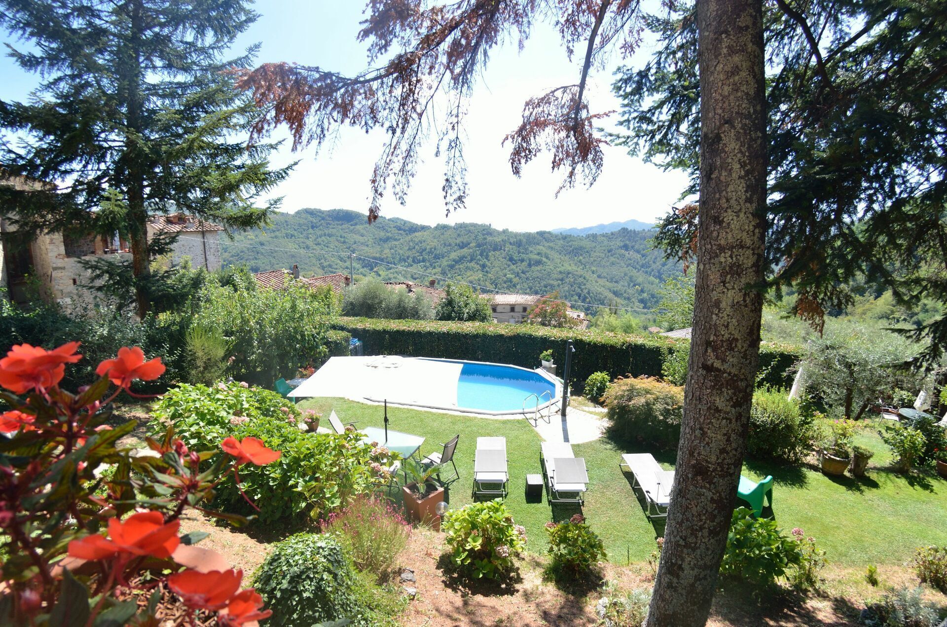 Una piscina con vista su un paesaggio montuoso, circondata da vegetazione e alberi.