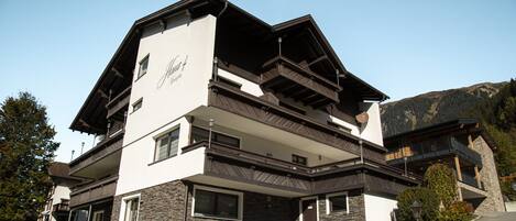 A multi-story hotel with a modern design, featuring balconies and a stone facade.