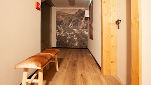 A hallway with wooden flooring, a bench, a door, and a wall mural of a mountain landscape. - 1102 Kristall 2 (Gaschurn)