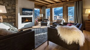 A cozy living room with a fireplace, comfortable seating, and large windows offering mountain views.