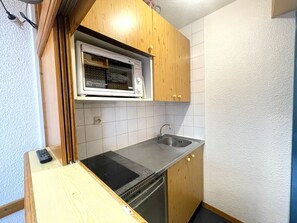 A compact kitchen with a built-in microwave, a sink, and wooden cabinets. - Studio for 4 in Valfréjus, balcony, TV, ski locker (Valfréjus)