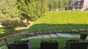 Un espace extérieur aménagé avec un sentier en pierre, une rambarde en métal et des plantes en pot.