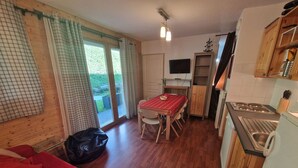 Un espace de vie compact comprenant un coin repas, une kitchenette et un canapé rouge.