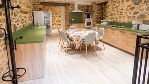 Een moderne keuken met een eethoek, stenen muren en een groen aanrecht.