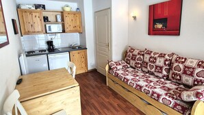 A compact kitchen with wooden cabinets, a microwave, a stove, and a dishwasher.