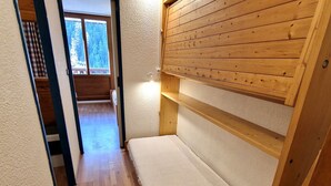A narrow hallway with wooden flooring and a bunk bed with a white mattress. - Studio for 4 in Valfréjus center with balcony, equipped kitchen, ski locker (Valfréjus)