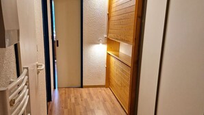 A narrow hallway with wooden flooring, a radiator on the left, and a wooden wall with a light fixture. - Studio for 4 in Valfréjus center with balcony, equipped kitchen, ski locker (Valfréjus)