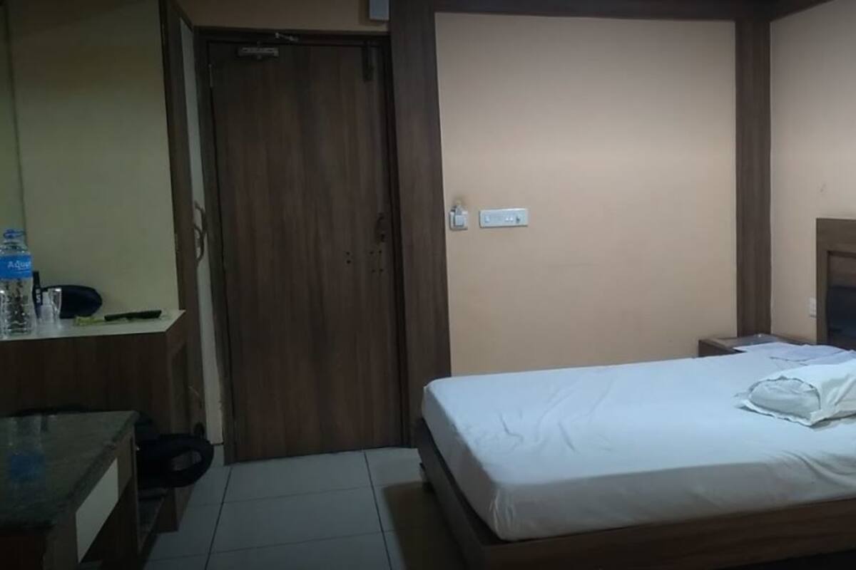 Ein kleines, ordentlich eingerichtetes Schlafzimmer mit einem Einzelbett, einem Nachttisch, einer Kommode und einem Holzschrank.