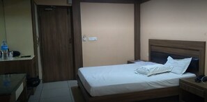 Un dormitorio pequeño y ordenado con una cama individual, una mesita de noche y un armario de madera.