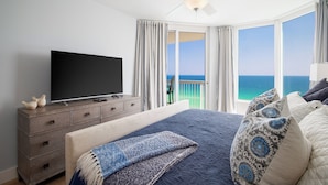 Ein Schlafzimmer mit einem großen Bett, einem Flachbildfernseher auf einer Kommode und einem Balkon mit Meerblick.