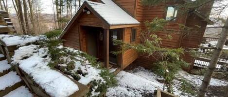 A wooden cabin with a small porch and a stone staircase leading up to it.