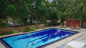 Ein rechteckiger Pool mit einer gefliesten Kante, umgeben von einem gepflasterten Weg und einer Backsteinmauer.