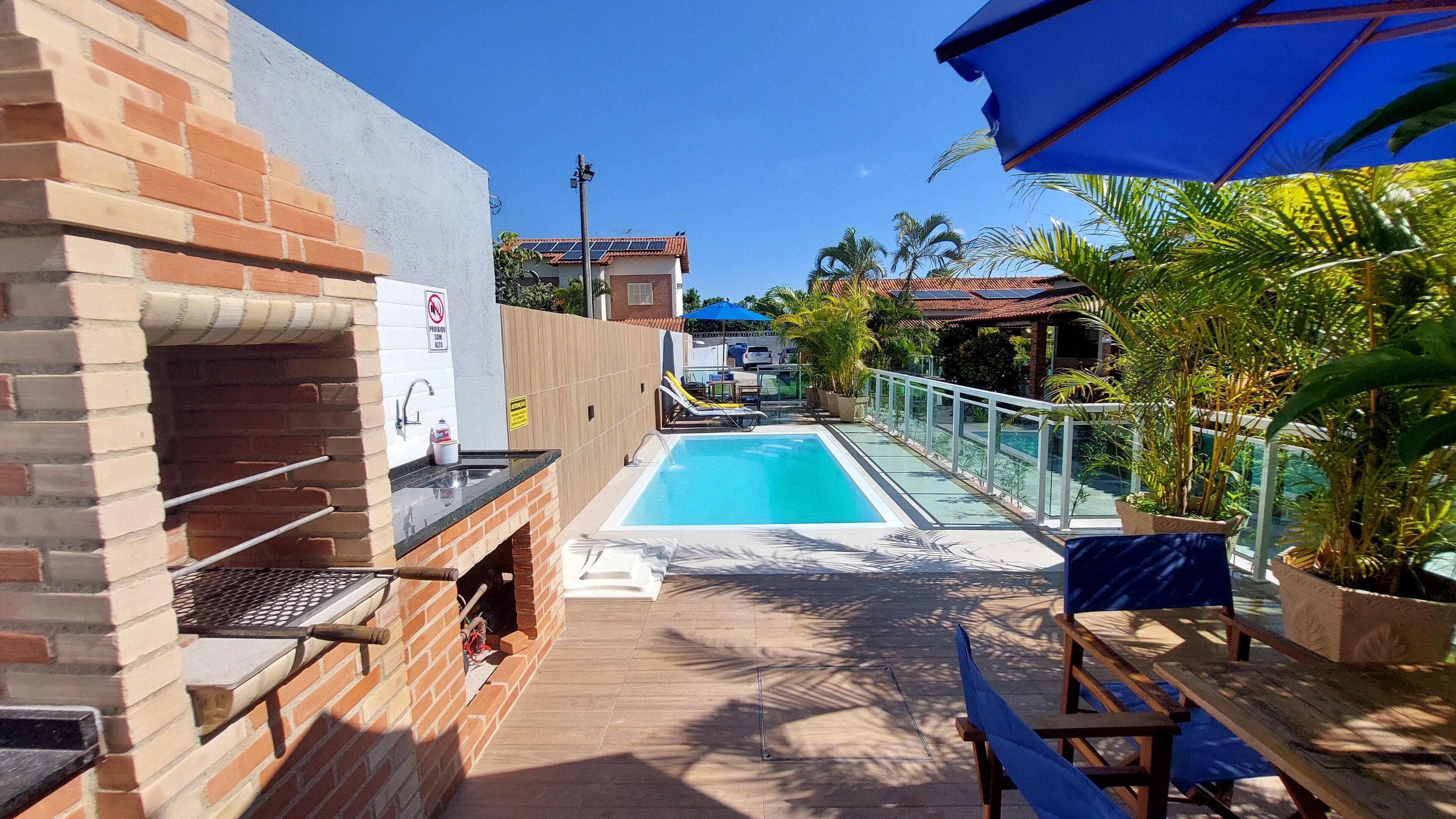Un espace extérieur avec une piscine, un barbecue, des chaises longues et des plantes en pot.
