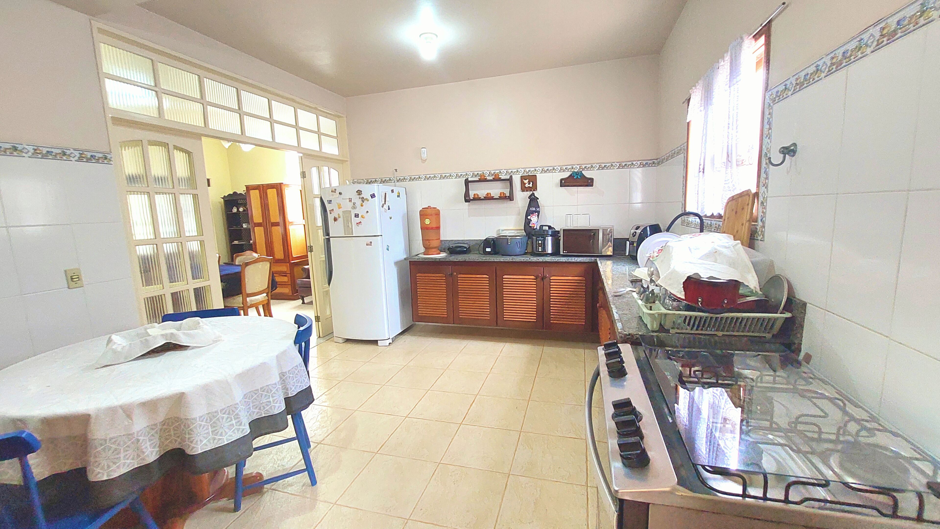 Una cocina con una mesa de comedor, sillas, un refrigerador, una estufa y alacenas.