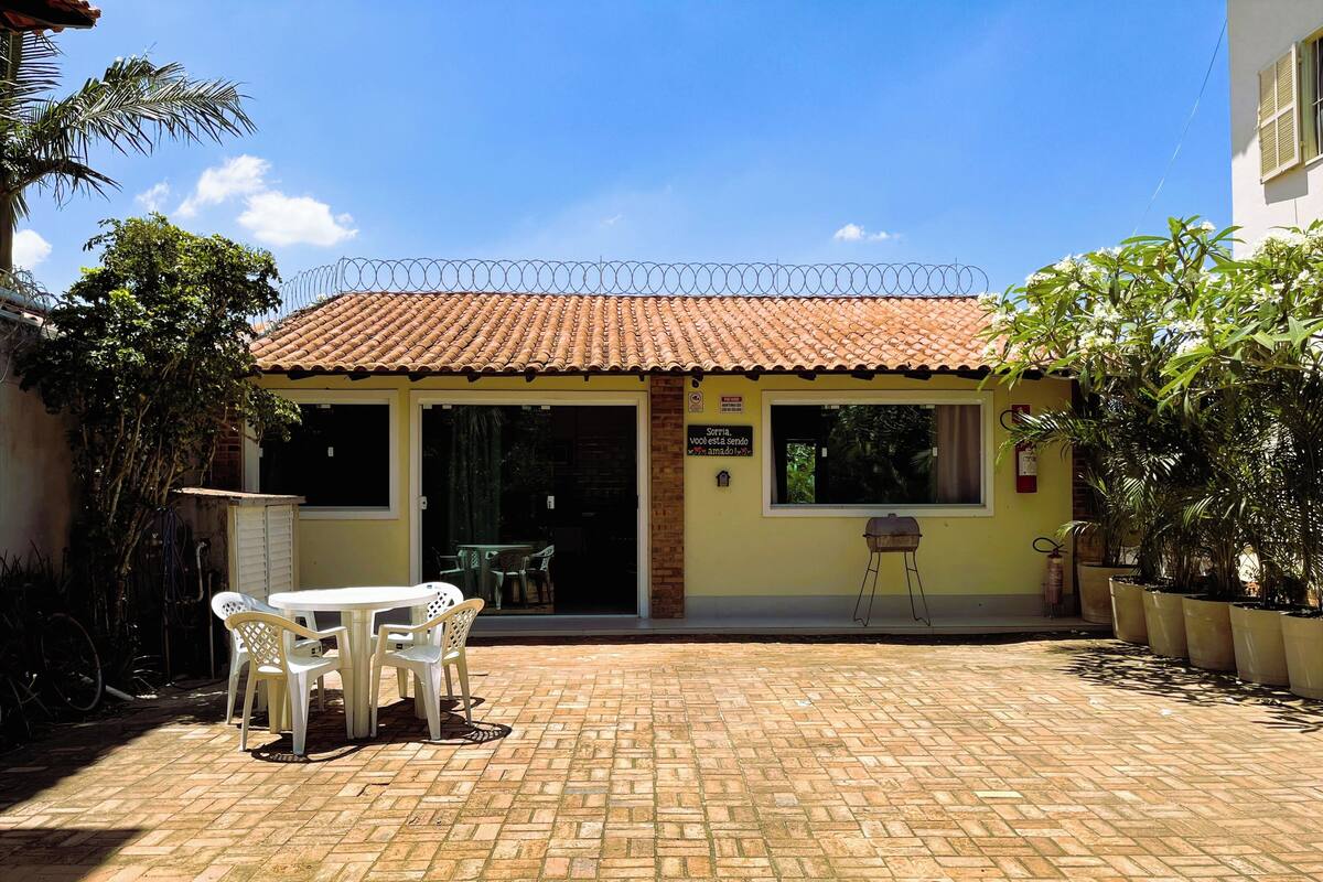 Un edificio con techo de tejas, un patio con mesa y sillas, y plantas en macetas.