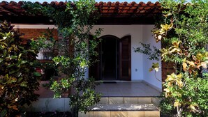 A building with a tiled entrance, a wooden door, and a red-tiled roof. - Village Itaúna Inn – Beach Houses (Saquarema)