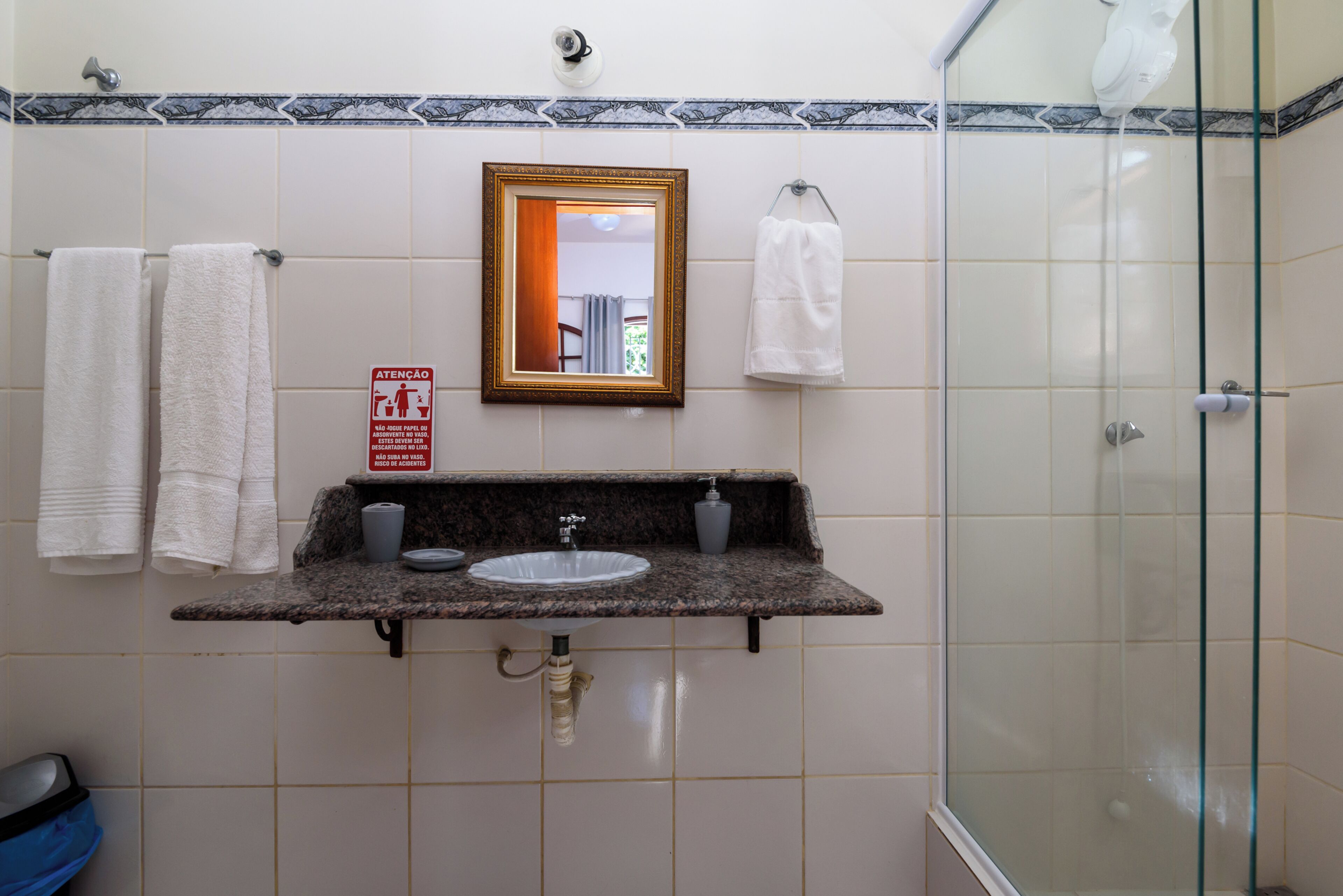 A bathroom with a sink, mirror, and two towels hanging on hooks.