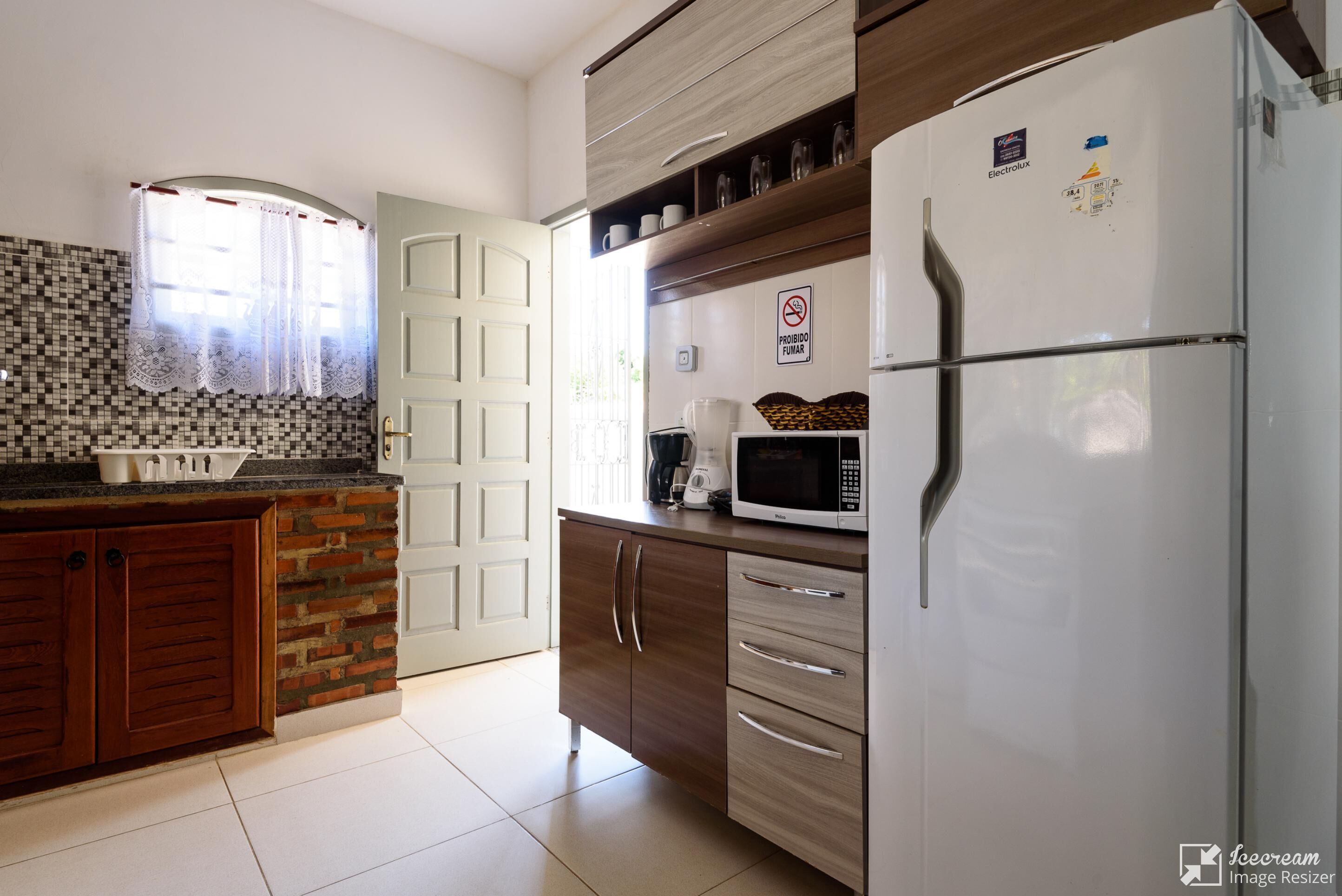 A kitchen with a refrigerator, microwave, and a coffee maker on the counter.